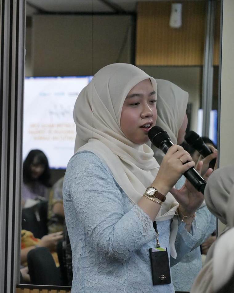 Seorang peserta berdiri memegang mikrofon dan angkat bicara di tengah sesi.