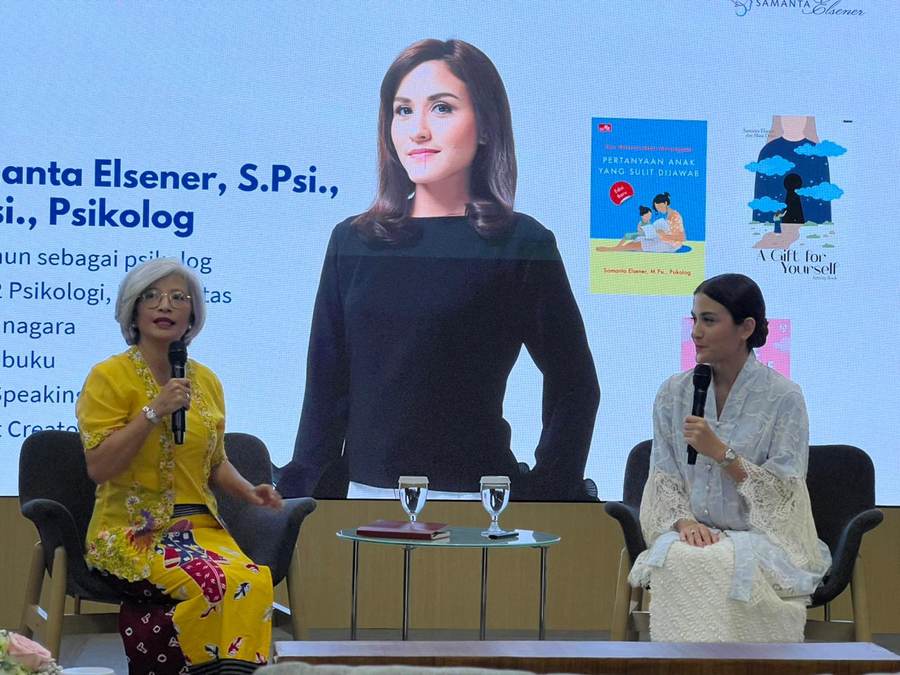 Dua pembicara duduk di panggung talkshow, layar di belakang menampilkan profil psikolog dan bukunya.