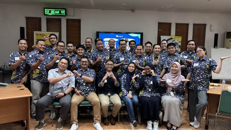 Puluhan karyawan berfoto bersama di akhir sesi, sebagian membentuk tanda hati dengan jari.
